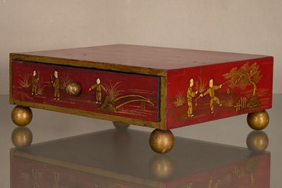 une boîte rouge ornée de motifs dorés, posée sur une table