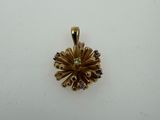 a gold pendant with a flower design on it