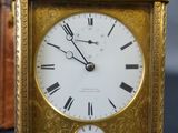 a gold clock with roman numerals on the face