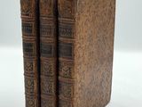 three old books are stacked on top of each other on a white surface