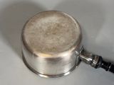 a silver pot with a handle on a white surface