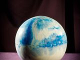 blue and white marble sphere sitting on top of a purple cloth