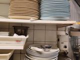 many plates and pans stacked on a shelf in a kitchen