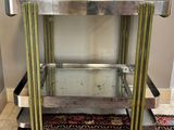 un chariot de bar en chrome et en verre posé sur un tapis dans une pièce