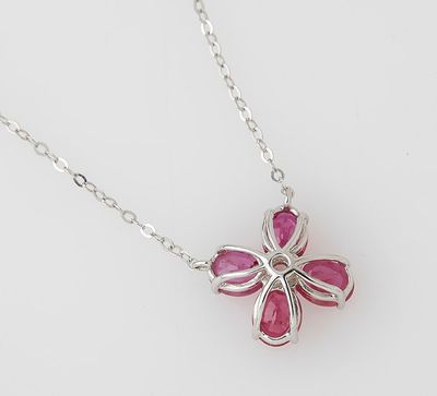a close up of a silver necklace with a pink flower on it