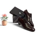une paire de chaussures en cuir marron pour homme, à côté d'une boîte ornée d'une fleur