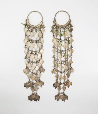 a pair of silver earrings with green beads and leaves