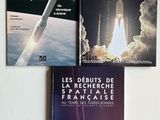 trois livres posés sur une surface blanche, avec une navette spatiale en arrière-plan