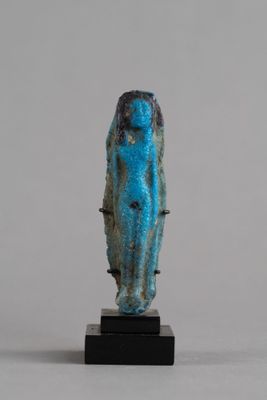 une statue égyptienne antique en pierre bleue représentant une femme, posée sur un socle noir