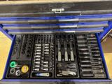 a blue tool box filled with tools sitting on top of a wooden floor