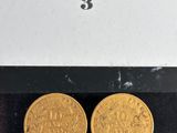 two gold coins in a box on a black surface