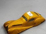 petite voiture jaune en plastique posée sur une surface blanche, avec une étiquette sur le côté