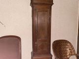 a grandfather clock sitting next to a chair in a living room