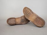 pair of brown leather shoes with studded soles on a gray surface