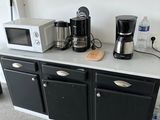 two microwaves and a coffee maker on a kitchen counter