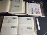 three open books sitting on top of a table covered in stamps