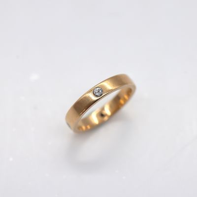 gros plan d'une bague en or surmontée d'un diamant