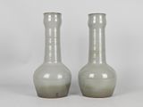 two gray vases sitting next to each other on a white surface