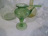 un vase en verre vert posé sur une table à côté d'autres bouteilles en verre