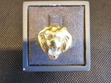 un gros plan d'un pendentif en forme de tête de lion en or, dans un écrin en argent