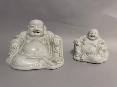 two statues of laughing buddhas sitting on a table