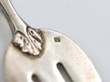 a silver fork with a flower on it on a white surface