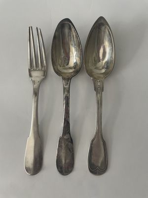 trois cuillères et une fourchette en argent sur une surface blanche