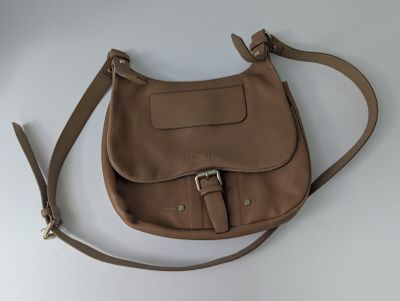sac à main en cuir marron avec une bandoulière et des boucles sur un fond blanc