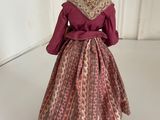 an old fashioned doll wearing a pink dress and a bonnet