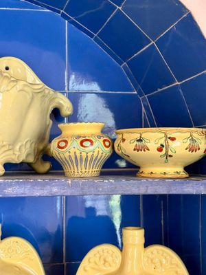 une étagère adossée à un mur carrelé de bleu et une étagère sur laquelle sont disposés des bols et des vases en céramique jaune