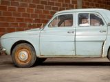 an old blue car parked in front of a brick wall