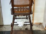 a wooden high chair with a basket on top of it