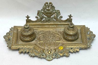 a gold plate with a pen and inkwell on it