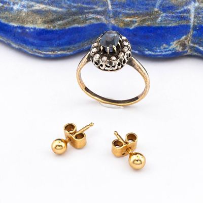 une photo représentant une paire de boucles d'oreilles et une bague posées sur un rocher