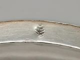 a close up of a silver plate with a leaf on it