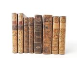 several old books are lined up in a row on a white surface