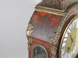 a red and gold clock sitting on a white surface
