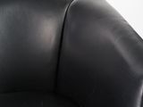 the back of a black leather chair against a white wall