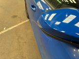 a blue car parked in a parking lot with its door open