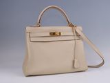 a white leather handbag with gold hardware on the handle