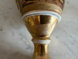 a gold vase with a picture on it sitting on a table