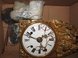 a gold clock in a box with other items in the background