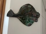 a metal fish sculpture on the wall of a house