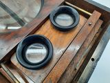 two old cameras sitting on a wooden table next to each other