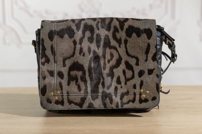 the small leopard print bag is on a wooden table