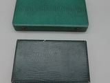 two green and black business cards cases sitting on a white surface