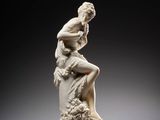 a white statue of a woman sitting on a rock