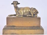 une statue représentant un mouton couché sur une caisse en bois