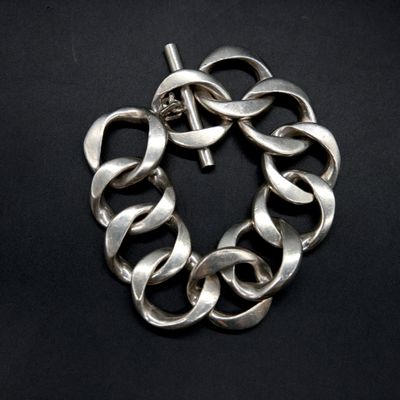 a close up of a silver bracelet on a black surface