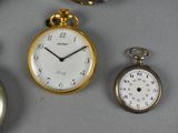 several different types of pocket watches are displayed on a table